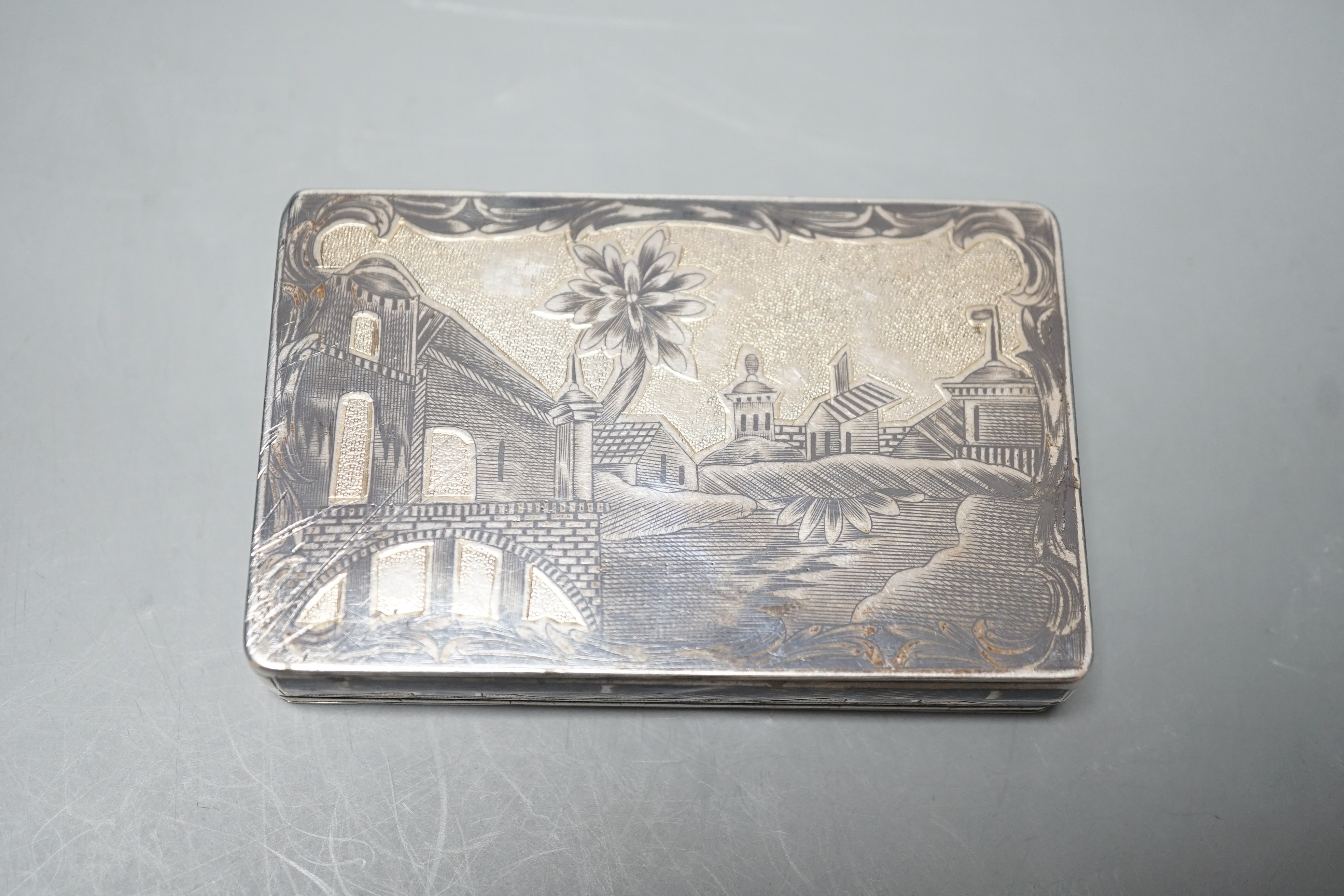 A late 19th century Russian 84 zolotnik and niello snuff box, decorate with figures in a landscape, 85mm.
